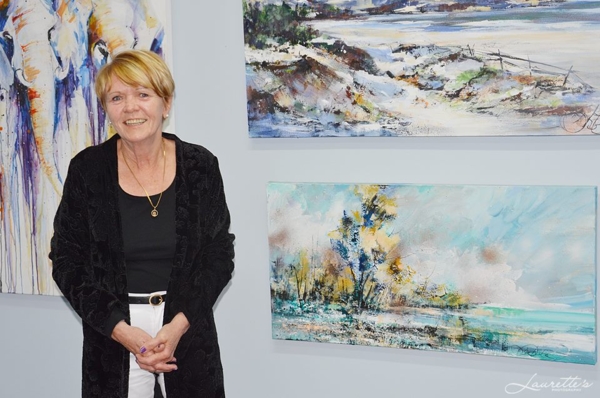 Diane White standing with artwork at an exhibition